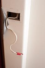 Domestic electric wiring during the renovation process with a taped off wire protruding from an access hole in the wall