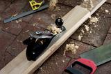 Woodworking tools with a wood plane, tenon saw and right angle or metal ruler on a nrick floor with a half planed plank of wood