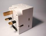 White plastic British electrical adaptor and plug fitting with a grounded earth, close up view