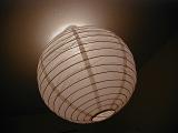 Lit paper and rattan globe lampshade glowing on a dark ceiling in a power, energy and interior decor concept