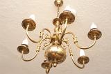 Brass ceiling chandelier with classical candle-style arms viewed from below in an interior decor concept