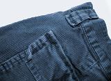 Close up detail of the textile and weave of a pair of blue corduroy trousers isolated on white