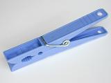 Spring-type blue plastic clothespin, symbol of household and laundry, close-up on gray