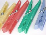Four colorful plastic clothes pegs on a white background conceptual of housework, cleanliness and laundry