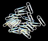Scattered pile of white paperclips for filing documents and making attachments lying on a black background, overhead, view