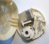 Smoke Detector with Open Casing Showing Different Components Affixed to White Ceiling