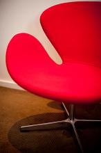 Modern red designer chair with a circular cut out modular design on a hardwood floor, only half visible