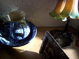 Old vintage objects with a blue and white pottery ewer and basin set, a sepia family portrait and Art Nouveau style lamp on a wooden cabinet