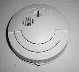 Modern white plastic circular smoke detector mounted on a wall or ceiling to act as an early warning in the event of fire
