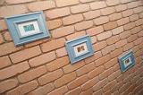 Series of three wall pictures in a diagonal display on a face brick wall taken at an oblique perspective