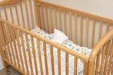Empty wooden baby cot or crib with colorful pattern linen in the corner of a romom, close up view