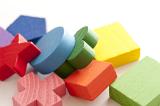Colorful educational wooden toy blocks in a variety of different basic geometrical shapes lying in a heap on white