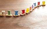 Still Life of Long Wooden Toy Train Towing Colorful Counting Cars with Numbers One Through Nine on Wooden Floor Surface with Copy Space