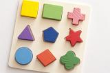 Kids educational wooden toy shapes puzzle with nine colorful basic shapes placed in matching cut outs on a board, high angle view