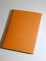 Blank orange kids school notebook lying closed on a grey background, viewed high angle