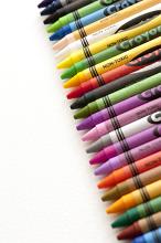 Neat diagonal line of multiple colored wax crayons in the colors of the spectrum arranged over a white background with copy space