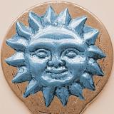 Decorative ceramic disc with a figural blue blazing sun with a face over a beige background in square format