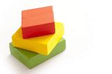 Red, yellow and green toy blocks stacked on white background with copy space