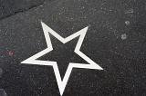 White five pointed star painted on a road or sidewalk conceptual of the walk of fame to honour celebrities