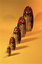 Set of Russian Matryoshka or Babushka dolls in a receding line arranged according to size on an orange background with copy space