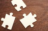 Three loose puzzle pieces lying on a wooden table with copy space in a concept of problem solving and answers