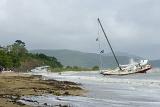 Shipwrecked yacht lies aground near the shore during storm wind in tropical sea