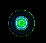 colourful concentric circles of spinning light, green and blue glowing on a black background