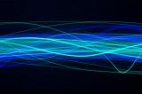 a complicated waveform pattern created from cyan and blue random and overlapping waves of light