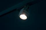 a single lit halogen track spotlight in a darkend room