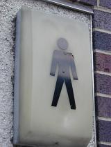 Gents public toilet sign with the silhouette of a man on a light unit mounted on an external wall of an outdoor ablution block offered as a service to the public