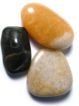 Smooth natural stones or pebbles with surfaces polished by the tumbling action of the water at the seaside or in a river bed, viewed from above on white
