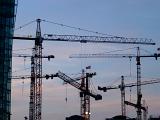 Group of heavy duty cranes on a construction site silhouetted against an evening sky conceptual of urban expansion and development