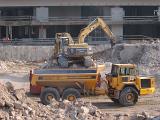 An industrial excavator and dump truck excavating and clearing rubble at a construction site