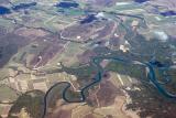 Aerial view of a riverine estuary and floodplain winding through fertile agricultural land and fields