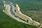 Dual lane carriageway with traffic winding through forested countryside in an environmental impact concept