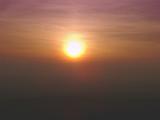 Sun setting in a hazy smoggy polluted sky with muted blended colours of orange and purple