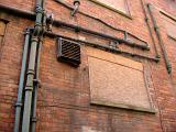 Old pipework and plumbing on the exterior of a red brick building