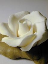 Yellow icing sugar rose to decorate a cake, close up view on grey