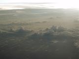 a layer of rain clouds with a low sun in the sky seen from the air