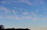 a sunset sky with a pink lit band of cirrus clouds