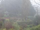 Scenic View of Tranquil Garden, Small Hut and Brick Wall Shrouded in Mist