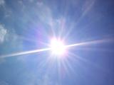 Sunburst in a blue sky with multiple clearly defined rays and genuine lens flare
