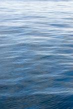 Background texture of calm rippling blue water with graduated light from dark in the foreground to light