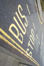 Bus Stop sign on the asphalt in yellow letters, marking the place on the road for public transport stops
