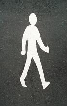 Pedestrian street crossing with a white sign of a walking man painted on asphalt viewed from above