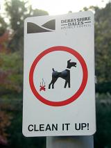 A close up of a council dog excrement sign in a park.