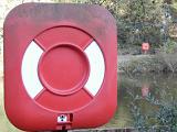Red and white life buoy or flotation aid mounted on an exterior wall ready for use in emergencies
