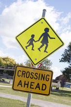 Pedestrian Crossing sign with children on a street warning traffic of an approaching crossing in a town or village