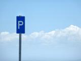 Blue parking sign on a tall pole against a cloudy blue sky with copy space