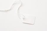White blank price tag or label with long string over a matching white background with copy space